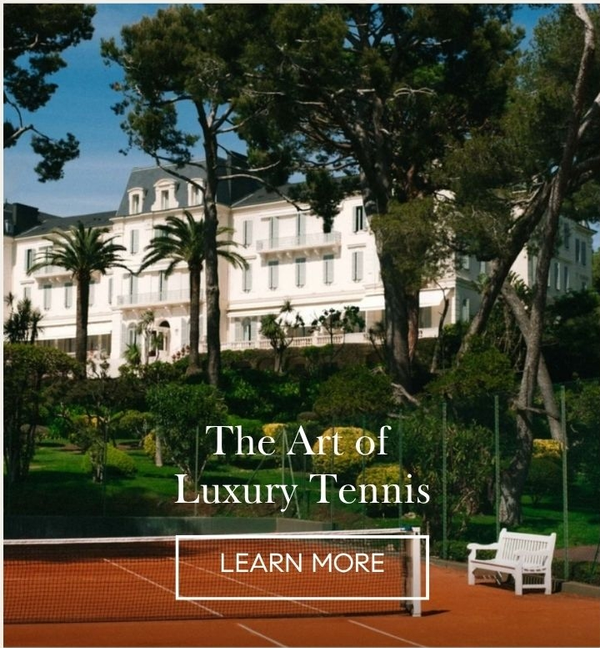 Clay tennis court below a white Riviera-style grand hotel among pines and palms, 'The Art of Luxury Tennis' with a Learn More button